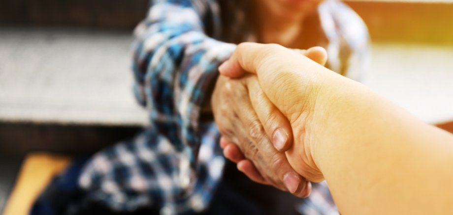 Close-up handshake for help homeless man on walking street in the capital city.